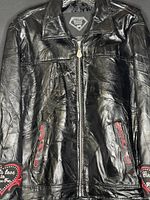 Front view of black genuine leather girls jacket with zipper closure, collar, and red embroidery on pockets and sleeves.