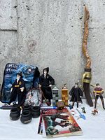 Overview photo of Harry Potter collection showing broomstick, backpacks, figures, cauldron, sticker books, and small collectibles on white surface with concrete wall background.