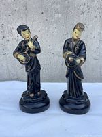 Front view of the two Japanese figurines, one holding a string instrument, the other a drum.