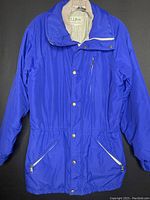 Front view of the blue LL Bean Penobscot Parka winter/fall coat laid flat showing zipper and snap button closure, zippered chest pocket, and zippered side pockets.