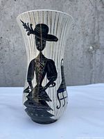 Front side view of Made In Italy vintage vase showing a black painted woman figure with a hat and stylized chair on white vertically striped background.