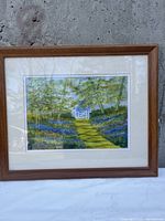 Photo of the framed landscape painting showing the full artwork and frame against a textured background.