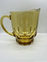 Side view of amber glass pitcher showing handle and pouring spout.