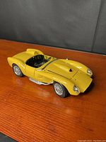 Yellow 1957 Ferrari 250 Testa Rossa scale model car showing angled front and side profile on wood surface.