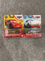 Photo showing two Disney Pixar Cars metal golden edition diecast cars in original packaging: Lightning McQueen and Dannen Castrop.