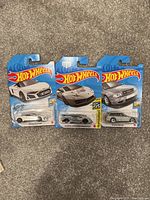 Photo of three Hot Wheels cars in their original packaging laid out on a carpet.