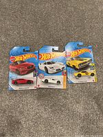 Three Hot Wheels toy cars in original packaging: Soulis IV (red), Acura NSX GT3 (white), Chevrolet Chevelle SS (yellow)