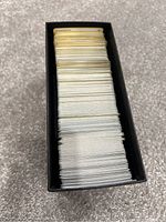 Top view of black Elite Trainer Box filled with a thick stack of Pokémon trading cards showing the back of the cards with the Poké Ball logo.