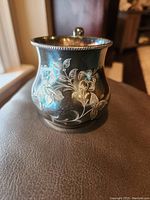 Front side view of the silver plated drinking cup showing detailed floral etching and beaded rim