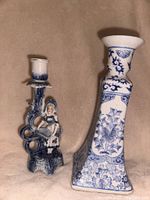 Two blue themed candle sticks on a beige surface, one with a floral pattern and the other with a female figurine detail.
