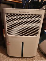 Front view of white Garrison dehumidifier showing perforated panel and water level indicator.