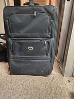 Front view of black wheeled suitcase with two zippered storage compartments on front.