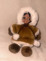 Photo showing Kipmik Anchorage Alaska girl doll wearing brown fur-trimmed parka with white fur lining and pom-poms, in excellent condition.