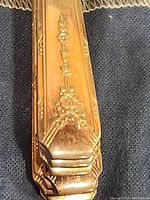 Close-up image of Oneida Milady silver plate flatware handle showing detailed floral and geometric embossed pattern.