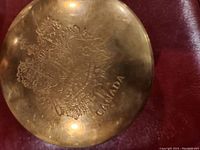 Top view showing the round brass lid with detailed engraved Canadian emblem and the word CANADA.