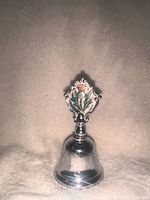 Front view photo of a silver souvenir bell with a colored Scottish thistle emblem on the handle.