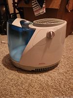 Sunbeam humidifier showing the main body and water tank on carpet flooring.
