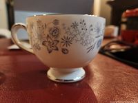 Side view of white Wedgwood teacup with blue floral design from the Belle Fleur pattern.