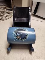 Front close-up of sled blue panel featuring hand-painted pine wreath and small pine cone