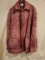 Full view of pink mohair and wool shawl hanging on hanger showing collar, front pockets, and fuzzy texture.