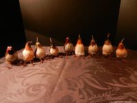 Front view of 9 assorted faux birds lined up showing variety in feather colors and details