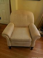 Front view of ivory wide back armchair showing padded arms, cushion seat, and caster wheels base.
