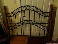 Full front view of black metal and wood queen size headboard and footboard with decorative curved metal elements and wood corner posts.