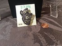 Front angle of the butterfly brooch on original 1928 card with penny for scale