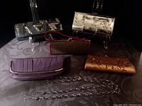 Overview of six vintage purses and the chain belt, showing variety of colors, material, and styles