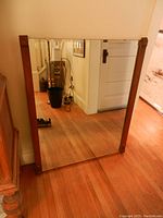 Full view of the wall mirror, showing wooden side frames and reflective surface in hallway setting.