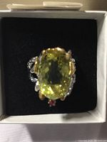 Front view of ring showing lemon quartz gemstone and ruby accent in box.
