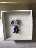 Top view of the amethyst and white CZ ring in white box showing three amethyst stones in pear, square, and rectangular cuts with CZ accents