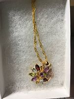 Flower-shaped multi-gem pendant with marquis cut stones on a gold over 925 chain, displayed in a white box with cushioning.