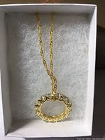 Aquamarine eternity ring on a gold-toned chain in white cushioned box, shown from top view