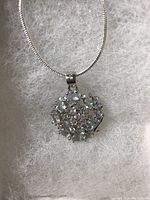 Close up of the oval cut light blue aquamarine and white cubic zirconia flower pendant on silver chain showing clarity and setting detail.