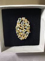 Top-down view of the oval-shaped ring featuring multiple aquamarine and CZ stones set on 14k gold over 925 silver, inside a white presentation box with black velvet insert.