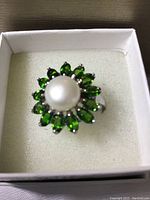Top-down front view of ring in box showing pearl center and surrounding diopside stones