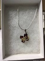 Pendant with red Mozambique garnet and white CZ stones arranged in floral design on a silver-tone chain in a box.