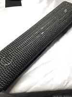 Full length of fine, thin silver diamond cut necklace displayed on textured black surface.