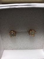 Pair of round 5mm fire opal stud earrings set in rose gold plated over 925 silver inside a white box with a cushion.