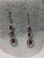 Front view of the earrings showing red pear cut rubies and sparkling white CZ stones on white gold over silver base