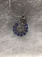 Close-up image of the oval cut tanzanite and CZ pendant with chain placed on soft padding.