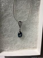 Close-up of pendant showing oval London blue topaz stone and white cubic zirconia on 14k white gold over sterling silver.