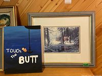 Two art pieces displayed side by side: framed print with horse and carriage and hand painted canvas with humorous text