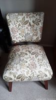 Front view of upholstered chair showing floral upholstery and wooden legs