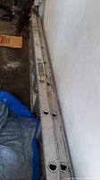 Full view of extension ladder lying against wall with visible aluminum rungs/logo.