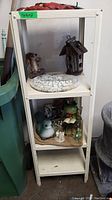 Full view of white shelf holding garden decor items including wooden birdhouse, garden stone, and figurines.