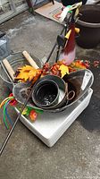 Lot showing metal hanging basket rod, pails stacked, decorative bird and artificial leaves, garden tools, and foam base