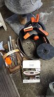 Photo of garden tools including hand fork, trowel, sprinkler, and metal buckets on concrete floor