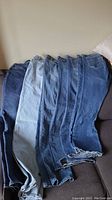 Five pairs of women's blue denim jeans laid out side by side showing color variations and cuts.